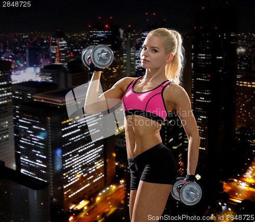 Image of sporty woman with heavy steel dumbbells