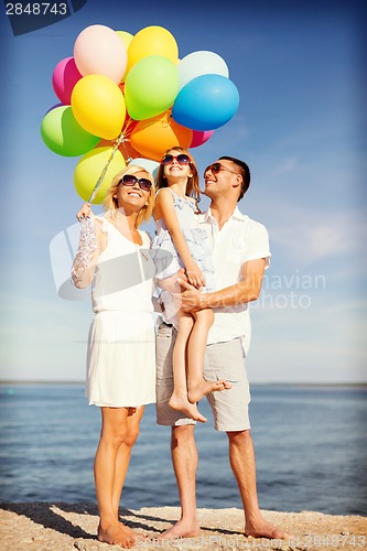 Image of happy family with colorful balloons at seaside