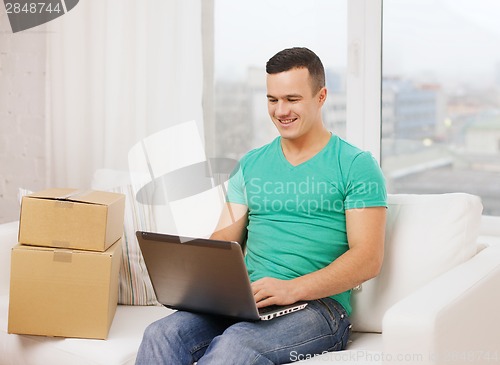 Image of man with laptop and cardboard boxes at home