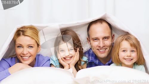 Image of happy family with two kids under blanket at home