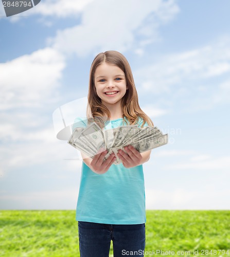 Image of smiling little girl giving dollar cash money