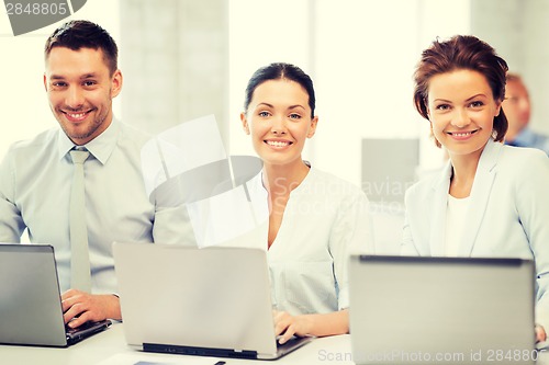 Image of group of people working with laptops in office