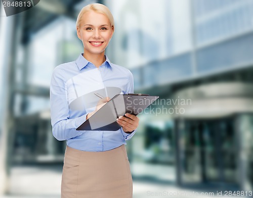 Image of smiling woman taking notes in the city center