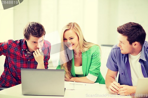 Image of smiling students looking at laptop at school