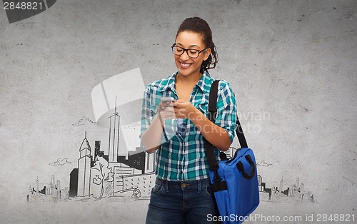 Image of student in eyeglasses with smartphone and bag