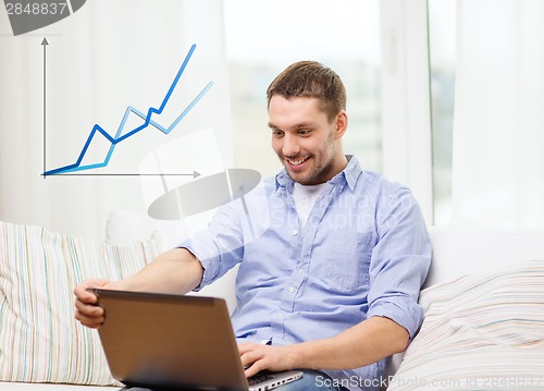 Image of smiling man working with laptop at home