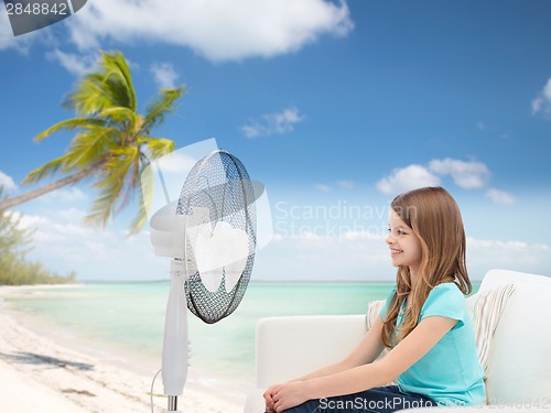 Image of smiling little girl with big fan at home