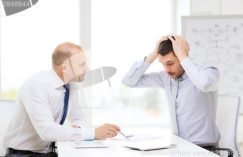 Image of two serious businessmen with tablet pc in office