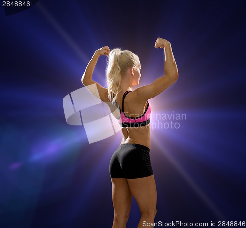 Image of sporty woman from the back flexing her biceps