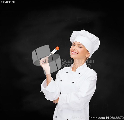 Image of smiling female chef with fork and tomato