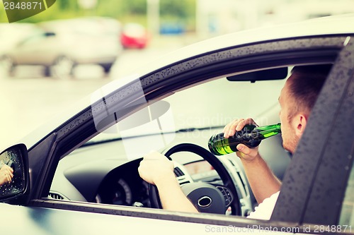 Image of man drinking alcohol while driving the car