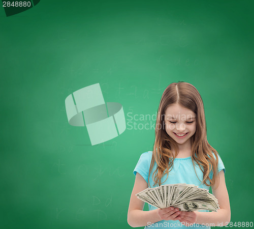 Image of smiling little girl looking at dollar cash money