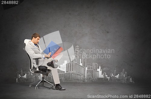 Image of handsome businessman with folders sitting on chair