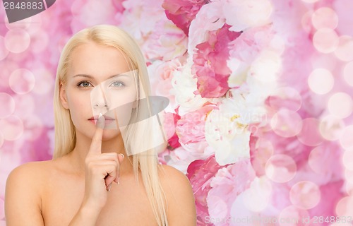 Image of calm young woman with finger on lips