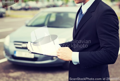 Image of man with car documents outside