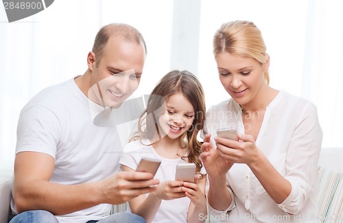 Image of parents and little girl with smartphones at home