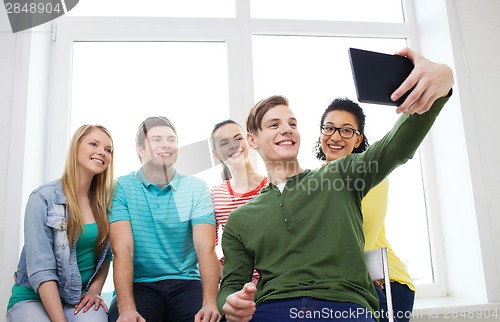 Image of smiling students making picture with tablet pc