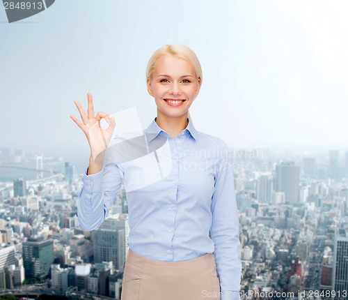 Image of smiling businesswoman showing ok-sign with hand