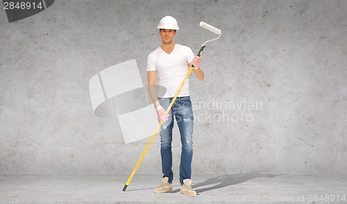 Image of handsome painter in helmet with paint roller