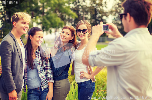 Image of teenagers taking photo with digital camera outside