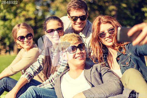 Image of teenagers taking photo with smartphone outside