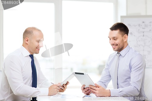 Image of two smiling businessmen with tablet pc in office