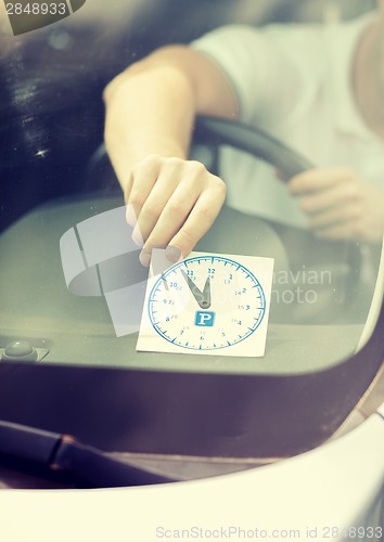 Image of man placing parking clock on car dashboard