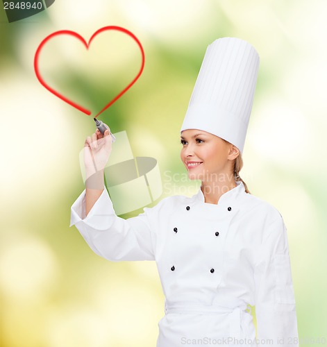 Image of smiling female chef writing something on air