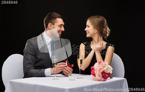 Image of man proposing to his girlfriend at restaurant