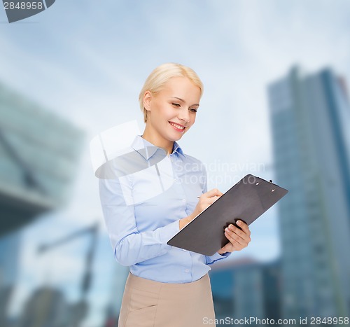 Image of smiling businesswoman with clipboard and pen