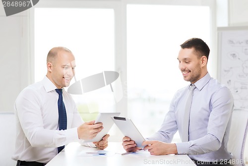 Image of two smiling businessmen with tablet pc in office