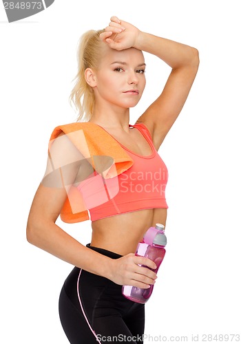 Image of tired sporty woman with towel and water bottle