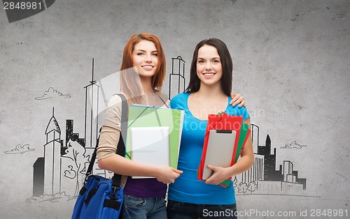 Image of two smiling students with bag, folders and tablet