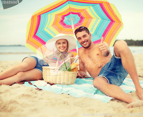 Image of smiling couple sunbathing on the beach