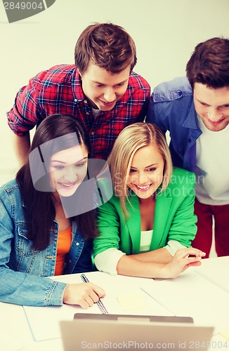 Image of smiling students looking at laptop at school