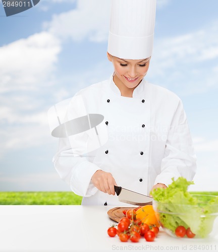 Image of smiling female chef chopping vegetables