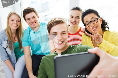 Image of smiling students making picture with tablet pc