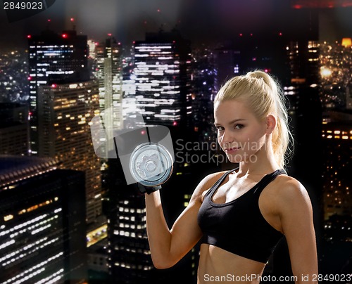 Image of young sporty woman with heavy steel dumbbell