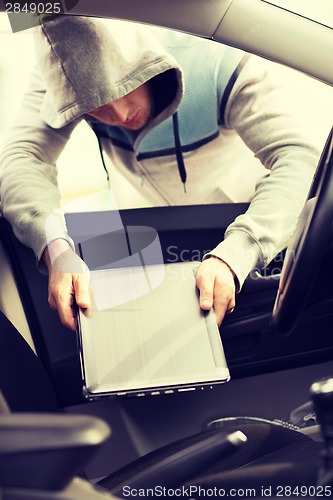 Image of thief stealing laptop from the car