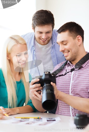 Image of smiling team with photocamera working in office