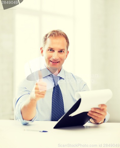 Image of businessman with papers showing thumbs up