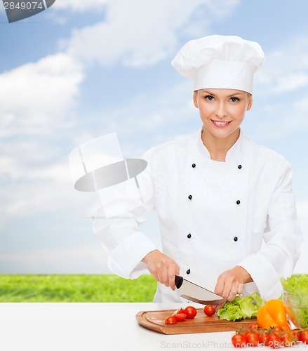 Image of smiling female chef chopping vegetables