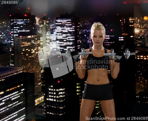 Image of sporty woman with heavy steel dumbbells