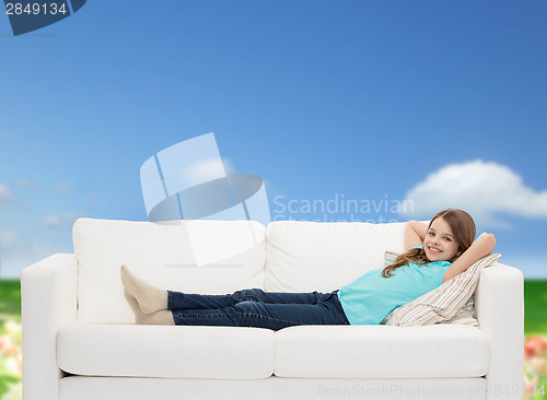Image of smiling little girl lying on sofa