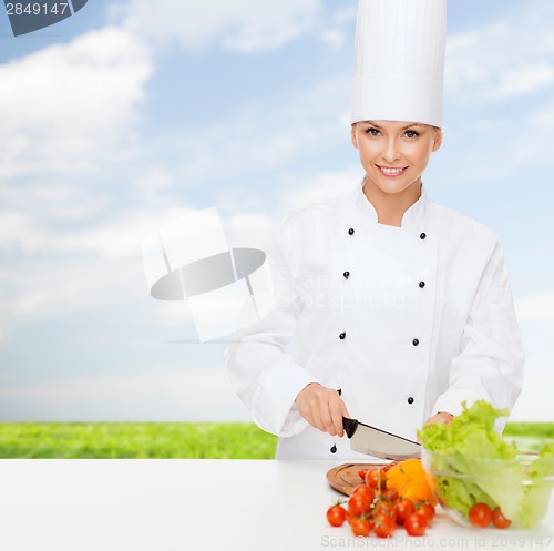 Image of smiling female chef chopping vegetables