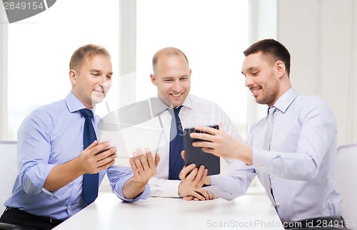 Image of three smiling businessmen with tablet pc in office