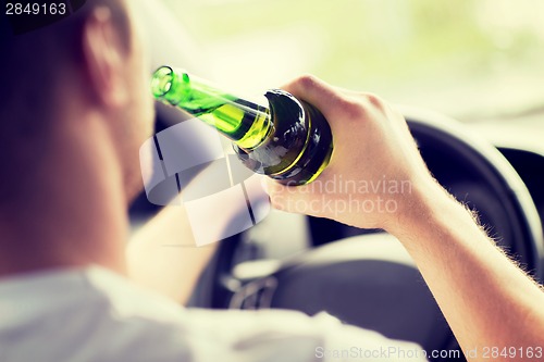 Image of man drinking alcohol while driving the car