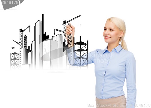 Image of smiling businesswoman drawing construction site