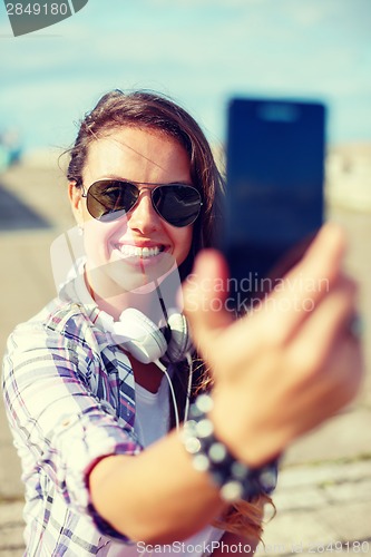 Image of smiling teenager taking picture with smartphone