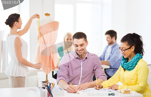 Image of smiling fashion designers working in office